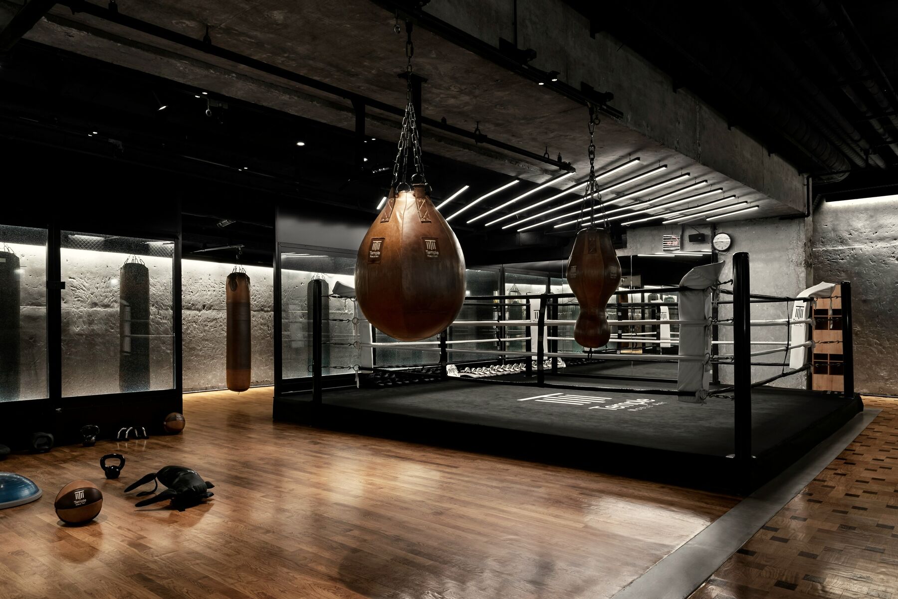 A boxing gym with leather bags hanging over a ring