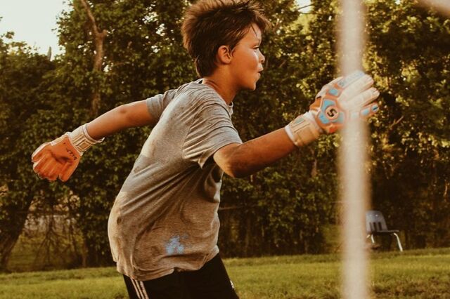 A young goalkeeper in gloves running in front of the net