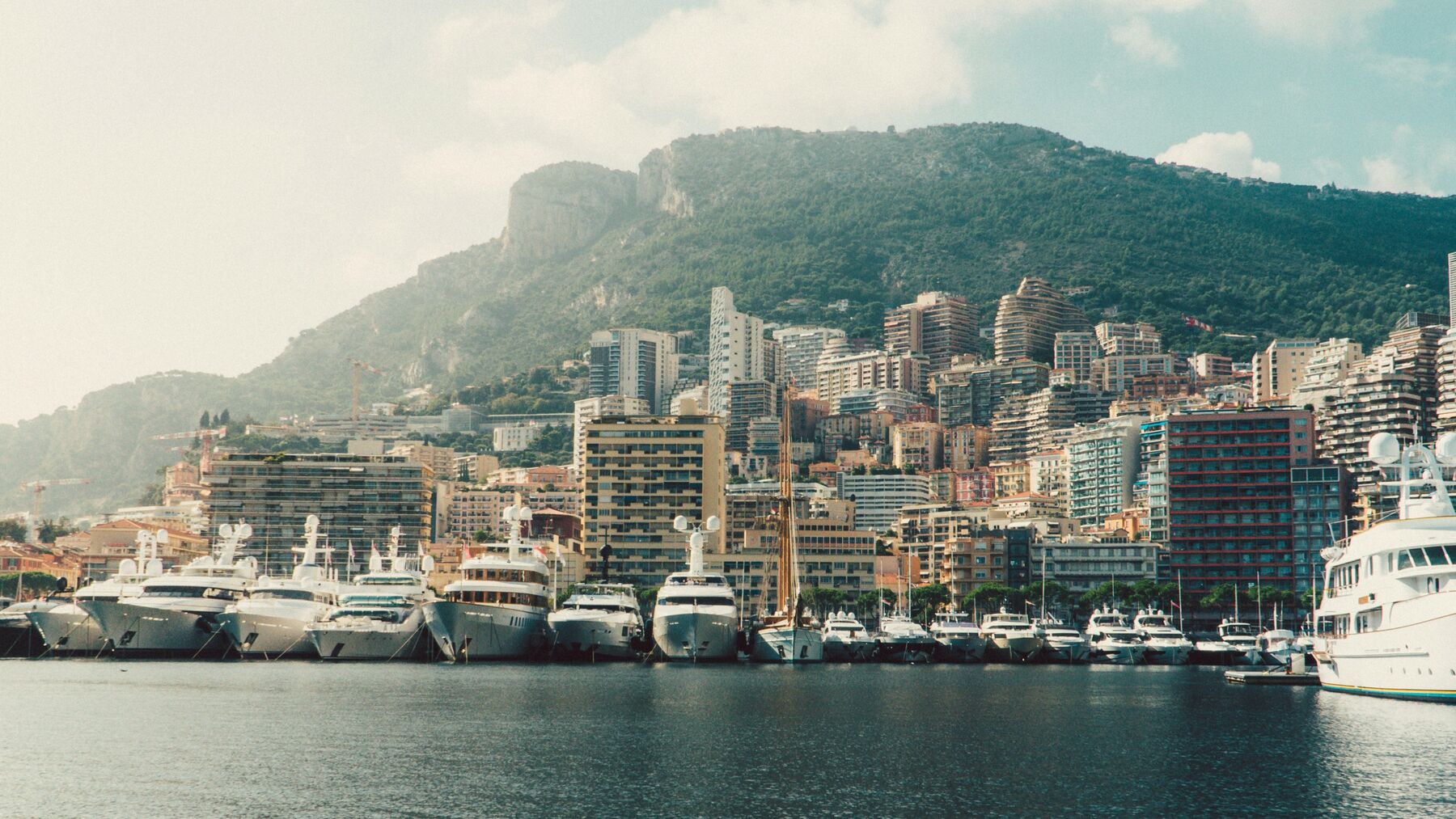 Yachts moored in the harbour of Monaco, with the hillside behind