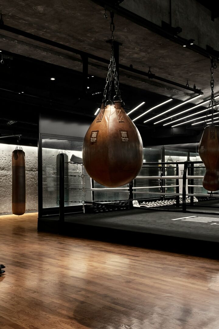 Boxing gym with leather bags hanging over a ring